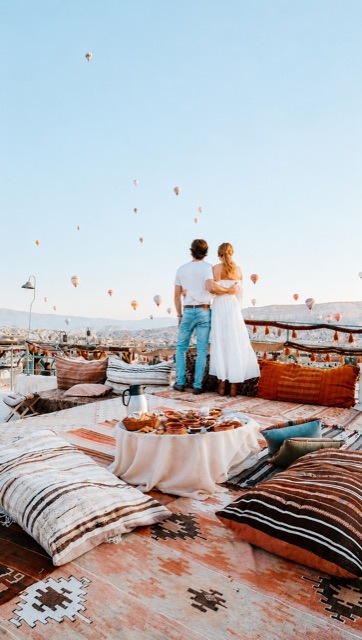 Jared and Lauren on a rooftop in Cappadocia, Turkey, watching hot air balloons rise over the valley at sunrise.